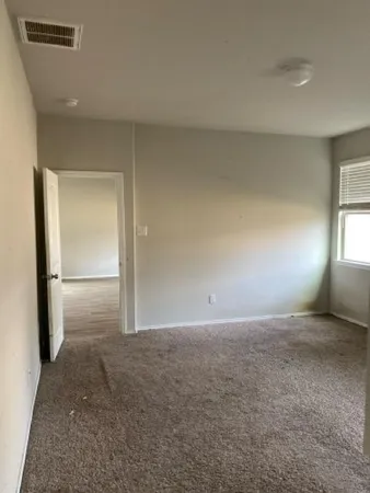 an empty room with windows and refrigerator