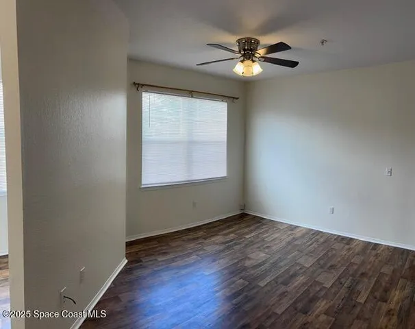 an empty room with a window and a fan