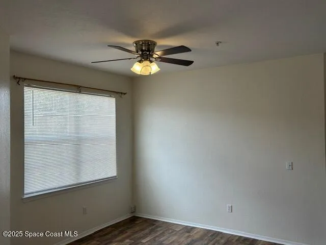 an empty room with a window and ceiling fan