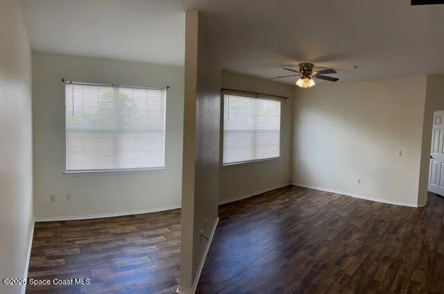 an empty room with wooden floor closet and windows
