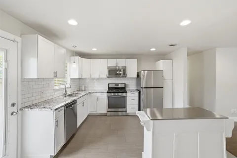 a kitchen with stainless steel appliances kitchen island granite countertop a refrigerator and a stove top oven