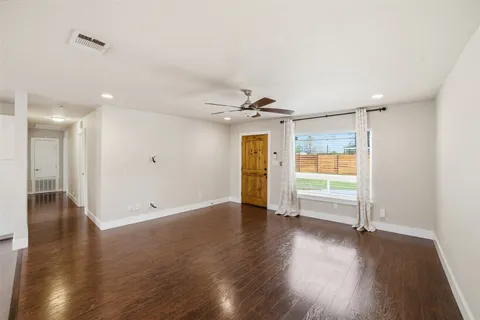 a view of empty room with wooden floor and window