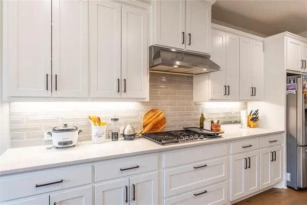 a spacious kitchen with stainless steel appliances kitchen island granite countertop a sink dishwasher a stove and a dining table with wooden floor
