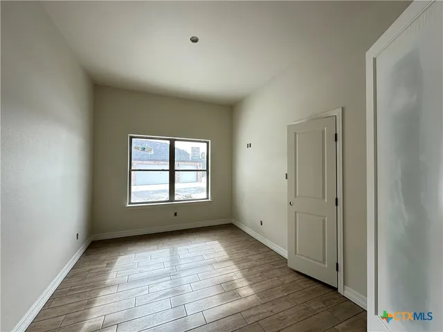 an empty room with wooden floor and windows