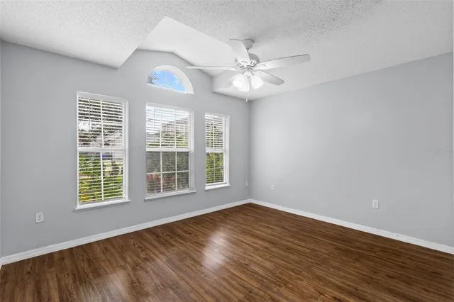 a view of an empty room with window and wooden floor