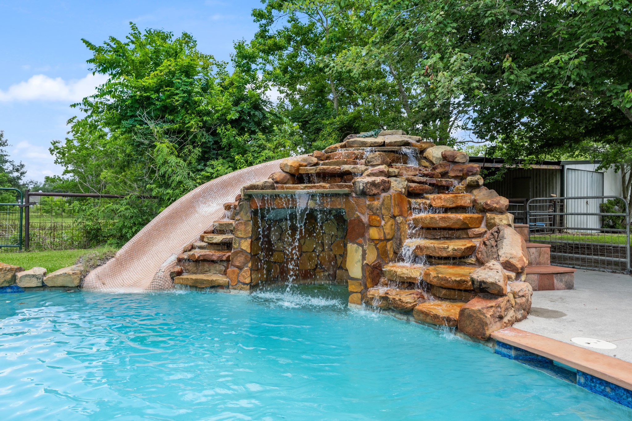 15602 Fir Road Santa Fe, TX 77517 - Photo 33 of 42 Resort-style pool feature with a custom rock waterfall, cascading water elements, and an impressive built-in slide that creates a true private retreat. Perfect for outdoor entertaining and summer fun.