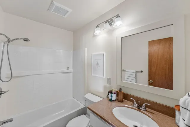 a bathroom with a granite countertop sink a mirror and a bathtub