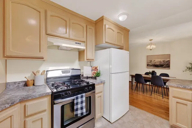 a kitchen with granite countertop a stove a refrigerator and a dining table