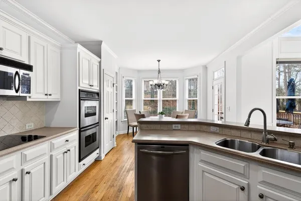a kitchen with stainless steel appliances granite countertop a refrigerator sink and white cabinets