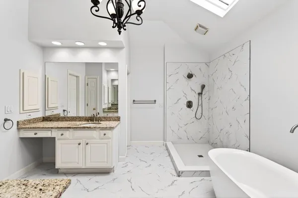 a spacious bathroom with a granite countertop sink mirror and bathtub