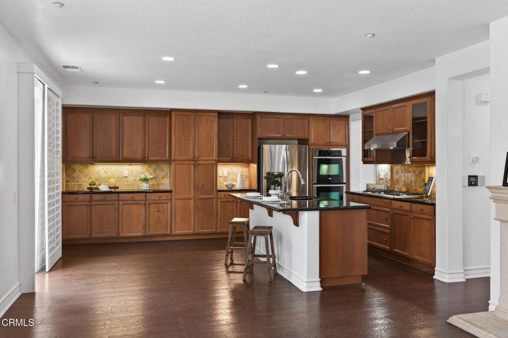 740 Freeport Lane Oxnard, CA 93035 - Photo 14 of 35 a kitchen with stainless steel appliances kitchen island granite countertop wooden floors and wooden cabinets