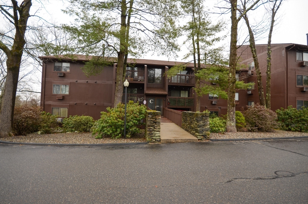 a front view of a house with a garden and tree