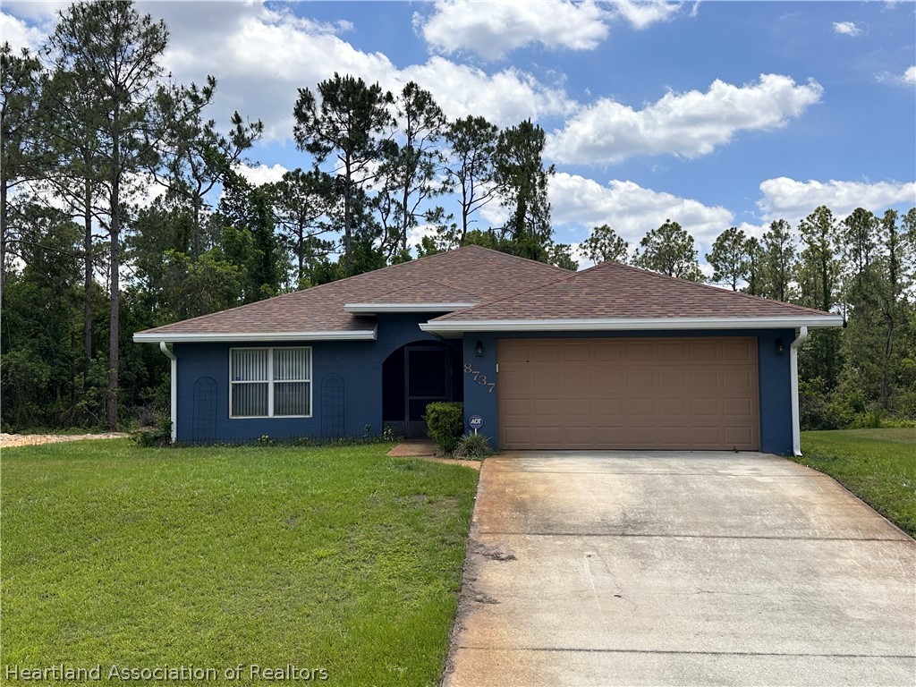 8737 Capilla Street Sebring, FL 33872 - Photo 1 of 43 a front view of a house with a yard and garage