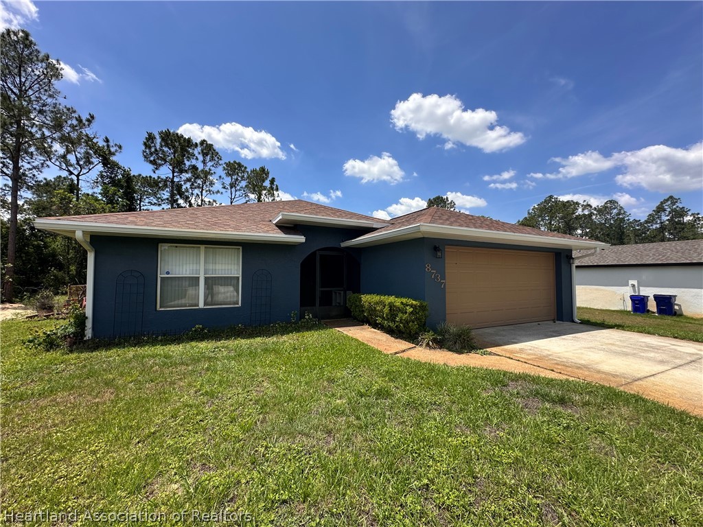 8737 Capilla Street Sebring, FL 33872 - Photo 2 of 43 a view of a house with a yard and garage
