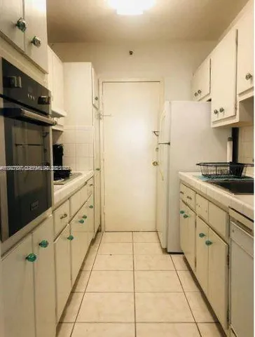 a kitchen with granite countertop a refrigerator and a stove top oven