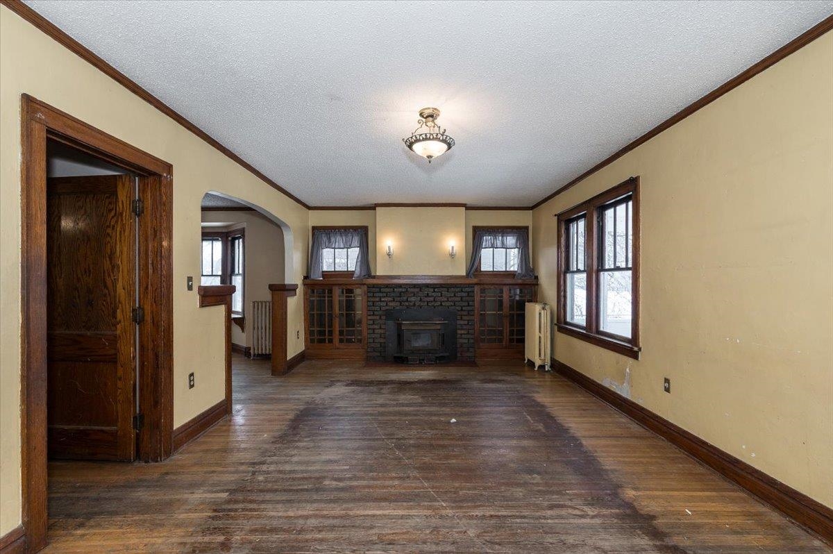 701 East 4th Street Superior, WI 54880 - Photo 2 of 16 Unfurnished living room featuring dark wood-style floors, arched walkways, plenty of natural light, crown molding, and radiator