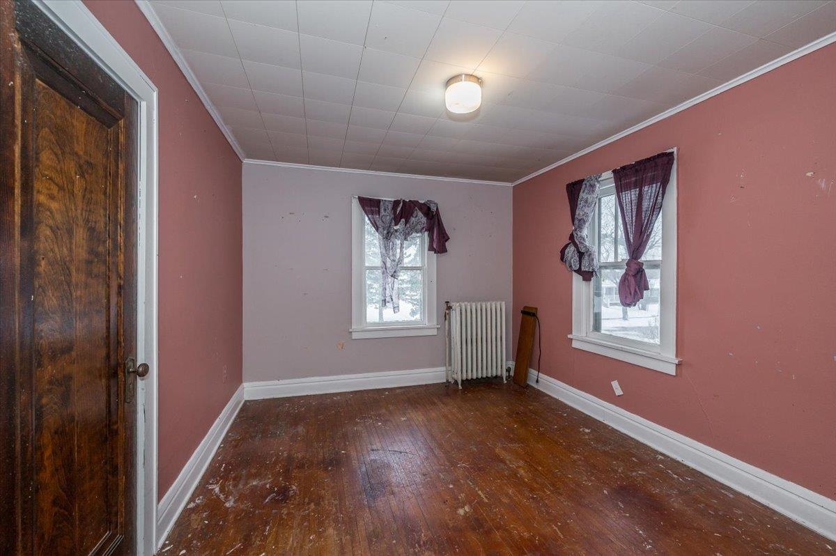 701 East 4th Street Superior, WI 54880 - Photo 8 of 16 Empty room featuring hardwood / wood-style flooring, radiator, plenty of natural light, and ornamental molding