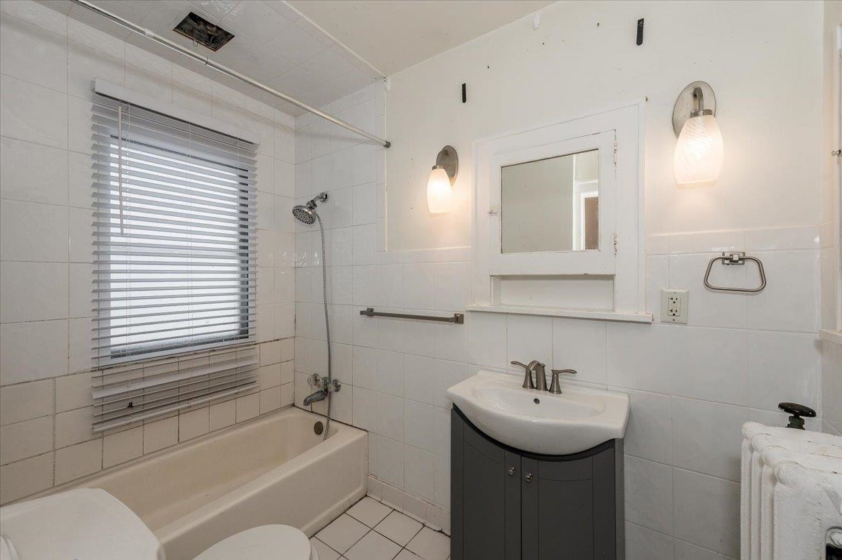 701 East 4th Street Superior, WI 54880 - Photo 9 of 16 Bathroom featuring vanity, shower / bath combination, tile walls, radiator heating unit, and light tile patterned floors