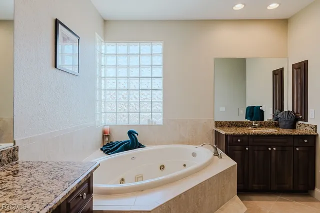 a bathroom with a granite countertop tub sink and mirror