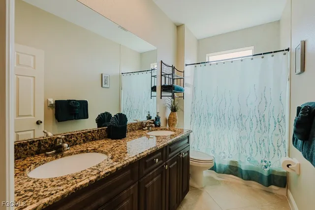 a bathroom with a granite countertop sink a toilet a mirror and shower curtain