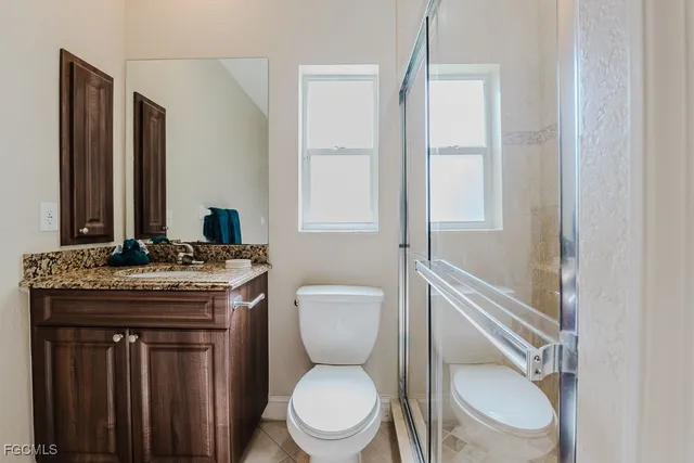 a bathroom with a granite countertop toilet sink and mirror