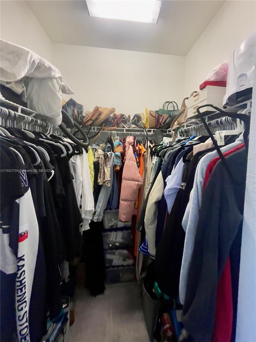 10005 Southwest 228th Terrace, Unit 10005 Miami, FL 33190 - Photo 11 of 12 a view of walk in closet with clothes and shoes