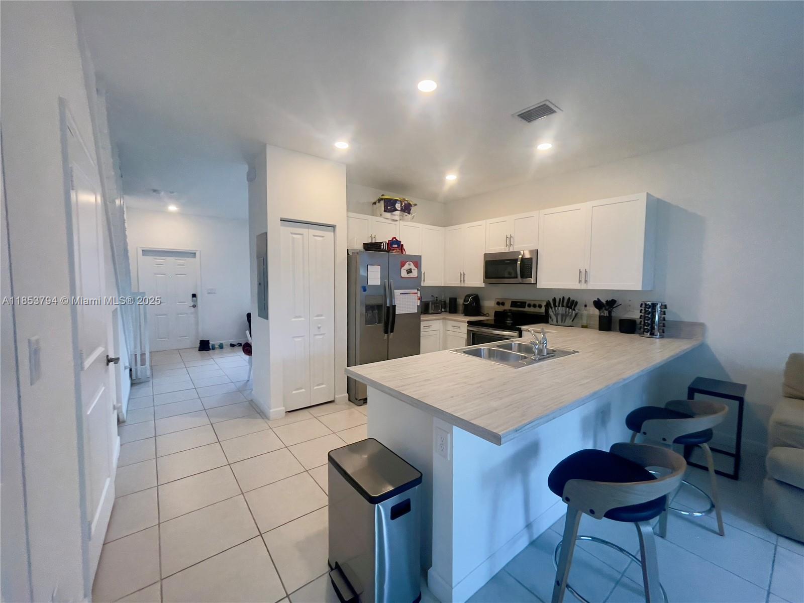 10005 Southwest 228th Terrace, Unit 10005 Miami, FL 33190 - Photo 2 of 12 a kitchen with stainless steel appliances a stove a refrigerator and a sink