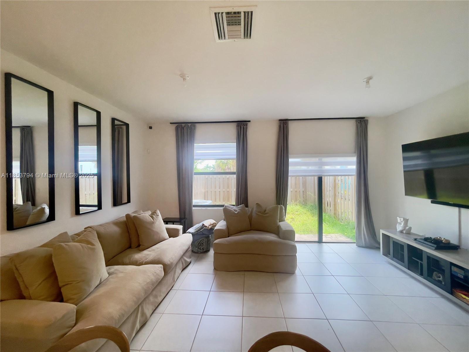 10005 Southwest 228th Terrace, Unit 10005 Miami, FL 33190 - Photo 3 of 12 a living room with furniture and a flat screen tv