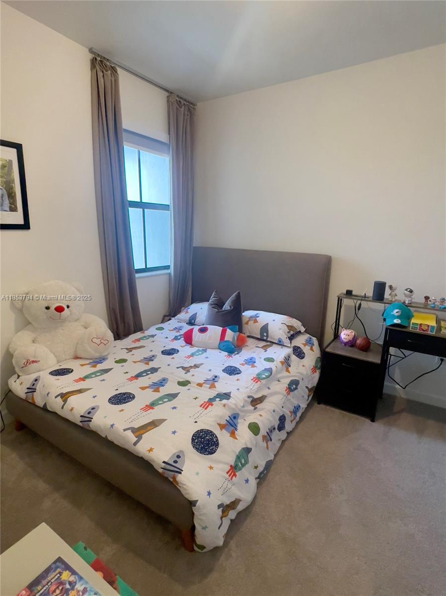 10005 Southwest 228th Terrace, Unit 10005 Miami, FL 33190 - Photo 7 of 12 a bedroom with a bed and a window