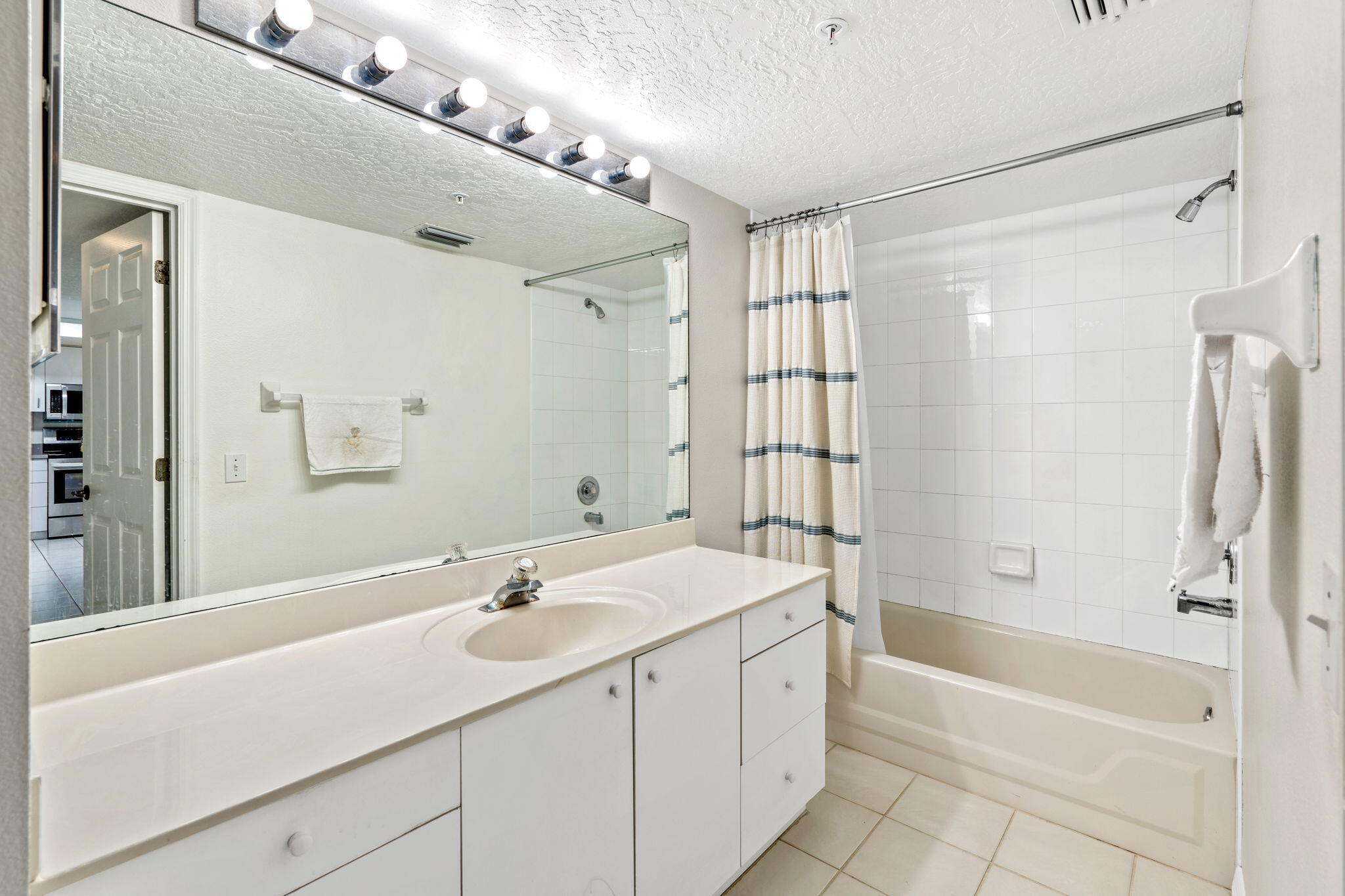 1505 North Hwy A1A, Unit 304 Indialantic, FL 32903 - Photo 16 of 27 a bathroom with a granite countertop sink a mirror a bathtub and shower
