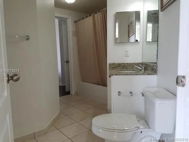 a white toilet sitting next to a bathroom sink and a mirror