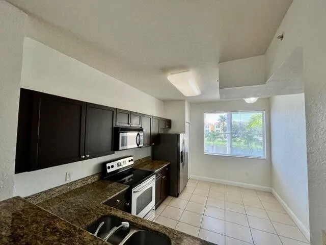 a kitchen with granite countertop a stove a microwave a sink and cabinets