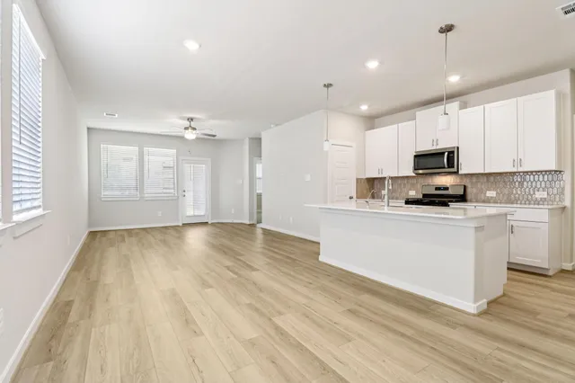 a kitchen with granite countertop a stove top oven a sink and white cabinets