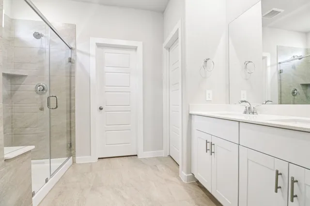 a bathroom with a double vanity sink mirror and shower