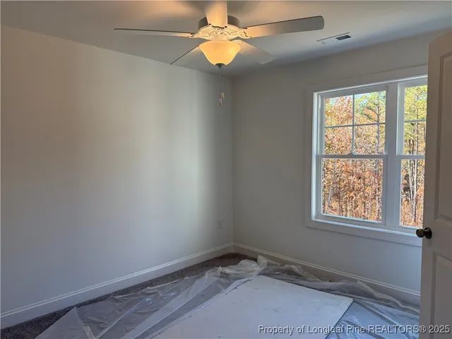 an empty room with windows and fan