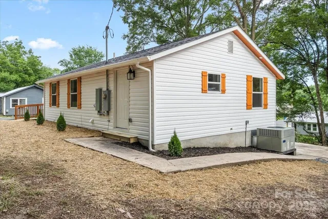 a view of a white house with a yard and large tree