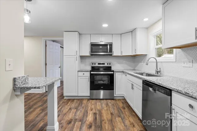 a kitchen with granite countertop a refrigerator stove top oven and sink