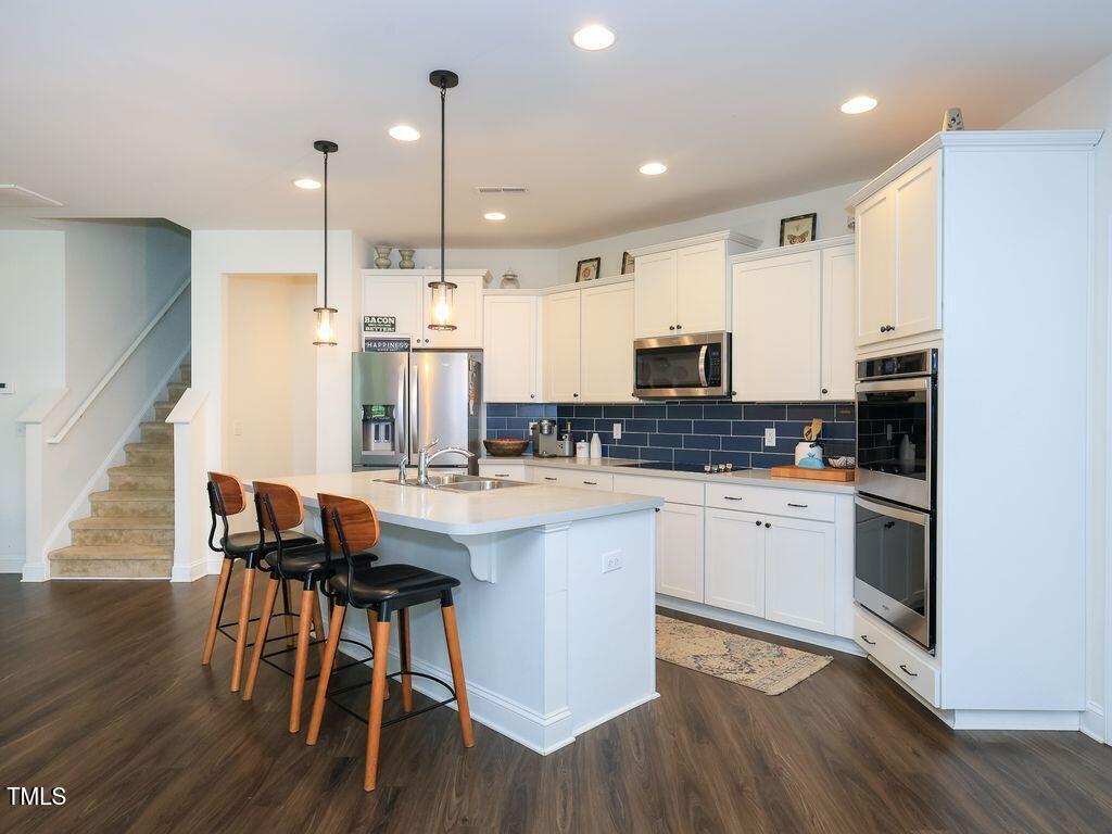 110 Point View Way Franklinton, NC 27525 - Photo 23 of 62 a kitchen with stainless steel appliances kitchen island granite countertop a stove a sink a refrigerator and white cabinets with wooden floor