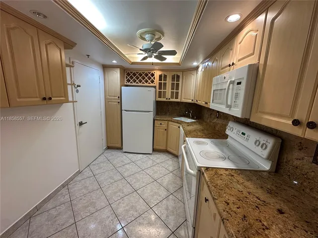 a kitchen with stainless steel appliances granite countertop a sink a stove a refrigerator a washer dryer and white cabinets