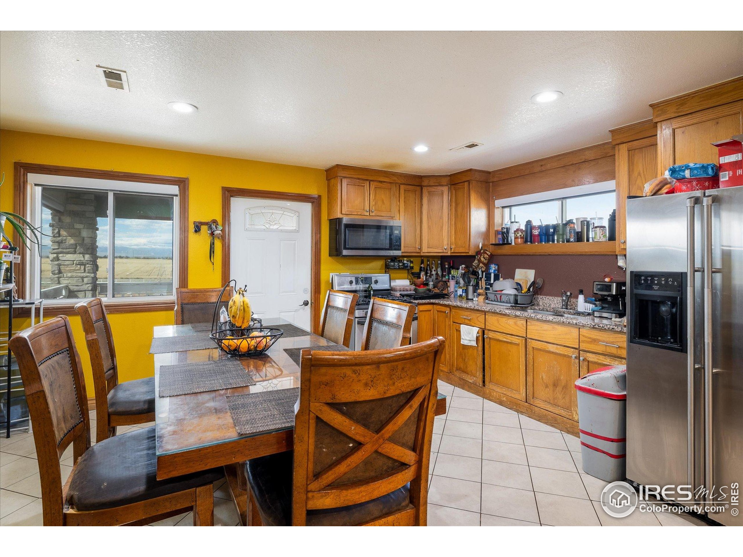 13400 Harvest Road Commerce City, CO 80022 - Photo 46 of 50 a kitchen with stainless steel appliances granite countertop a refrigerator a stove a sink a dining table and chairs with wooden floor