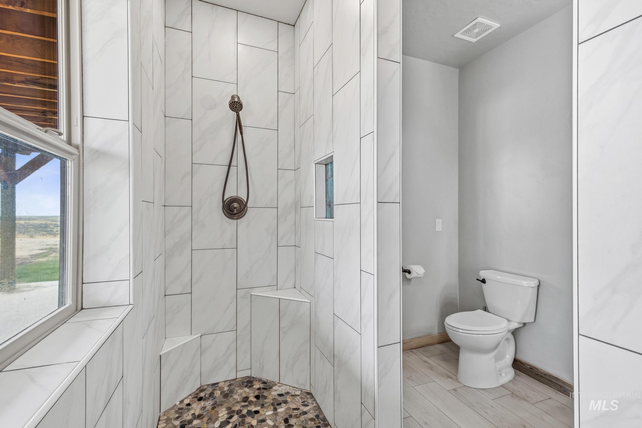 870 Desert Wind Road Boise, ID 83716 - Photo 21 of 50 Spacious shower featuring white subway tile, a built-in bench, a mosaic tile floor, and an integrated shower niche
