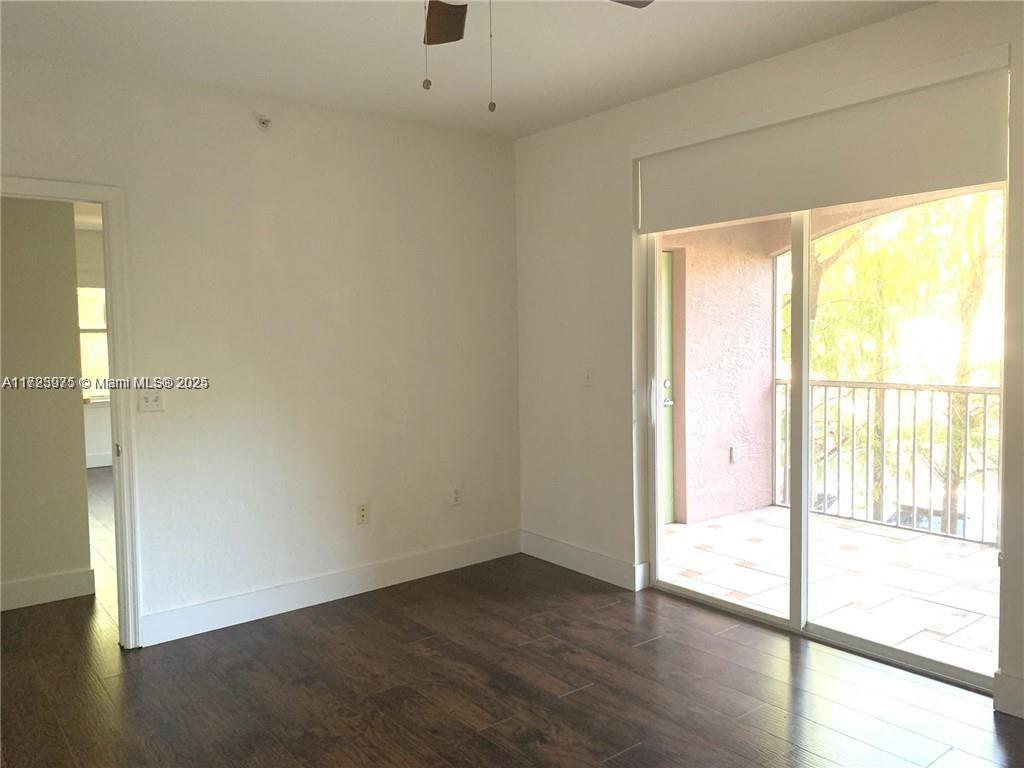 6776 West Sample Road, Unit 6776 Coral Springs, FL 33067 - Photo 8 of 20 a view of an empty room with wooden floor and a window