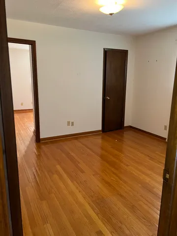 a view of an empty room with window and wooden floor