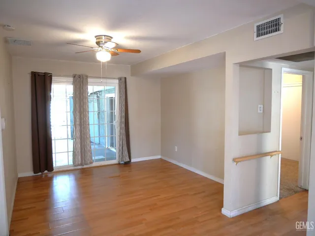 an empty room with wooden floor chandelier and windows