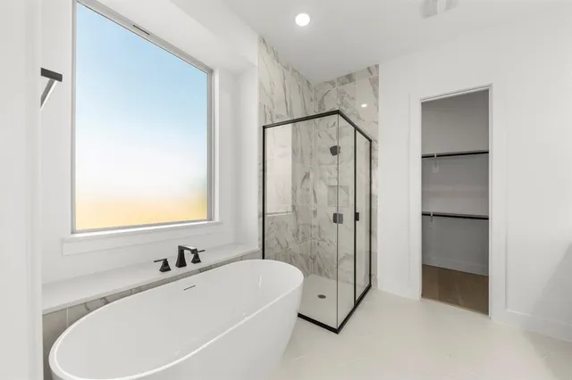 a bathroom with a tub sink shower and mirror