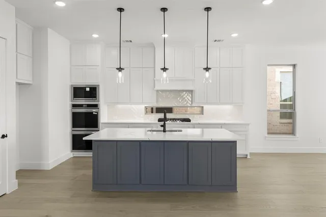 a kitchen with kitchen island a sink stainless steel appliances and cabinets