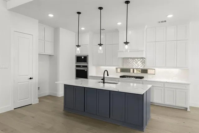 a kitchen with kitchen island a sink stainless steel appliances and cabinets