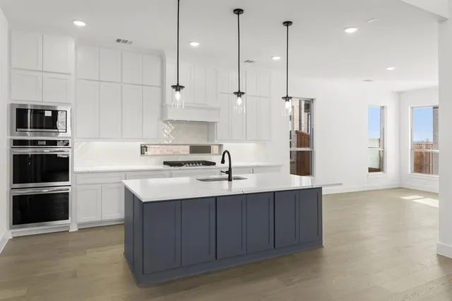 a kitchen with stainless steel appliances granite countertop a sink a stove and a refrigerator