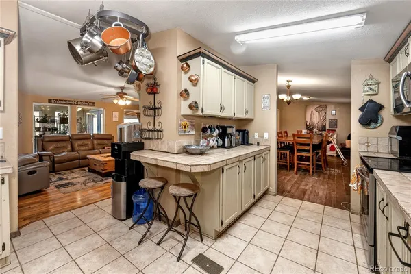 a kitchen with stainless steel appliances kitchen island granite countertop a sink a stove a dining table chairs and view of living room