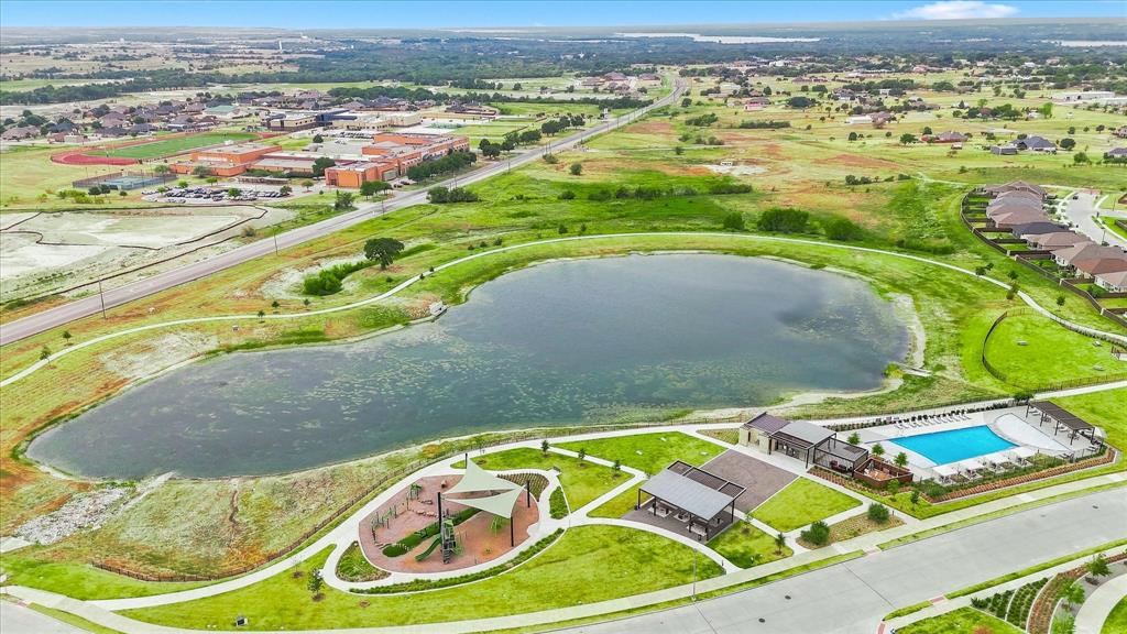 141 Medina Lane Rhome, TX 76078 - Photo 35 of 36 Community lake with surrounding green spaces, playground area, and aquatic center featuring a swimming pool